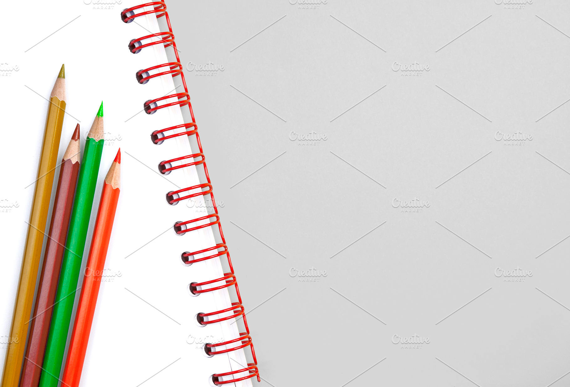 Colorful pencils on white notebook, a School & Education Photo by BOOCYS