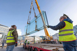 Workers install large glass panel using crane at construction site on a sunny d, an Industrial Photo by AlyaAnd