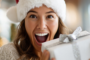 Joyful woman in a Santa hat holding, a Holiday Photo by MistyDay