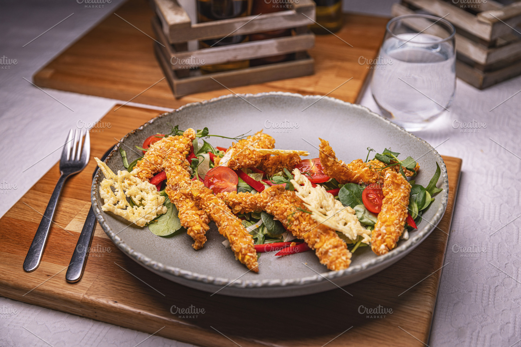 Breaded chicken strips topping fresh green salad, a Photo by Grafvision photography