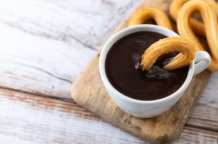 Traditional Spanish churros with hot chocolate breakfast on wooden table. Copy, a Food & Drink Photo by etorres69