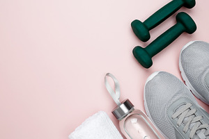 Gray sports shoes, green dumbbells, water bottle, and white towel on a pastel p, a Photo by matucha