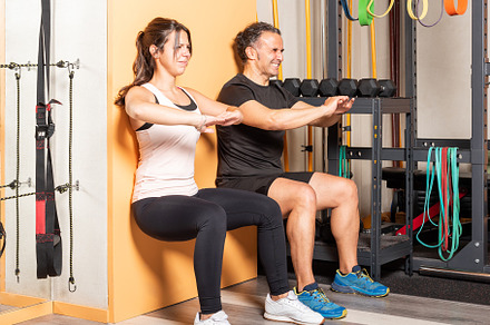 Athete people doing squats leaning on wall in gym, a Sports & Recreation Photo by Iván Moreno STOCK PHOTO