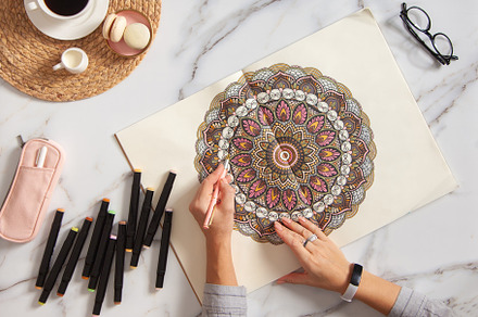 Woman drawing and coloring mandala in sketchbooks with colorful