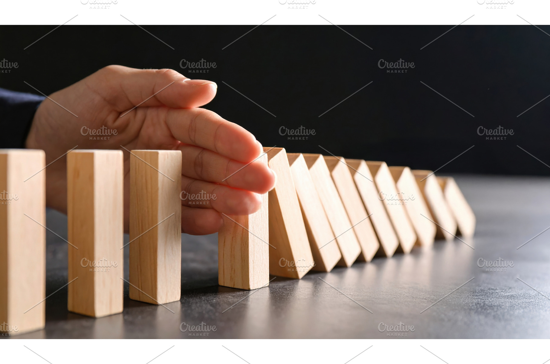 Human hand stopping falling dominoes, a Background Photo by Igor Tichonow