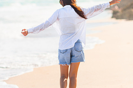 Young beautiful woman on beach vacation walking by the sea, a Person Photo by travnikovstudio