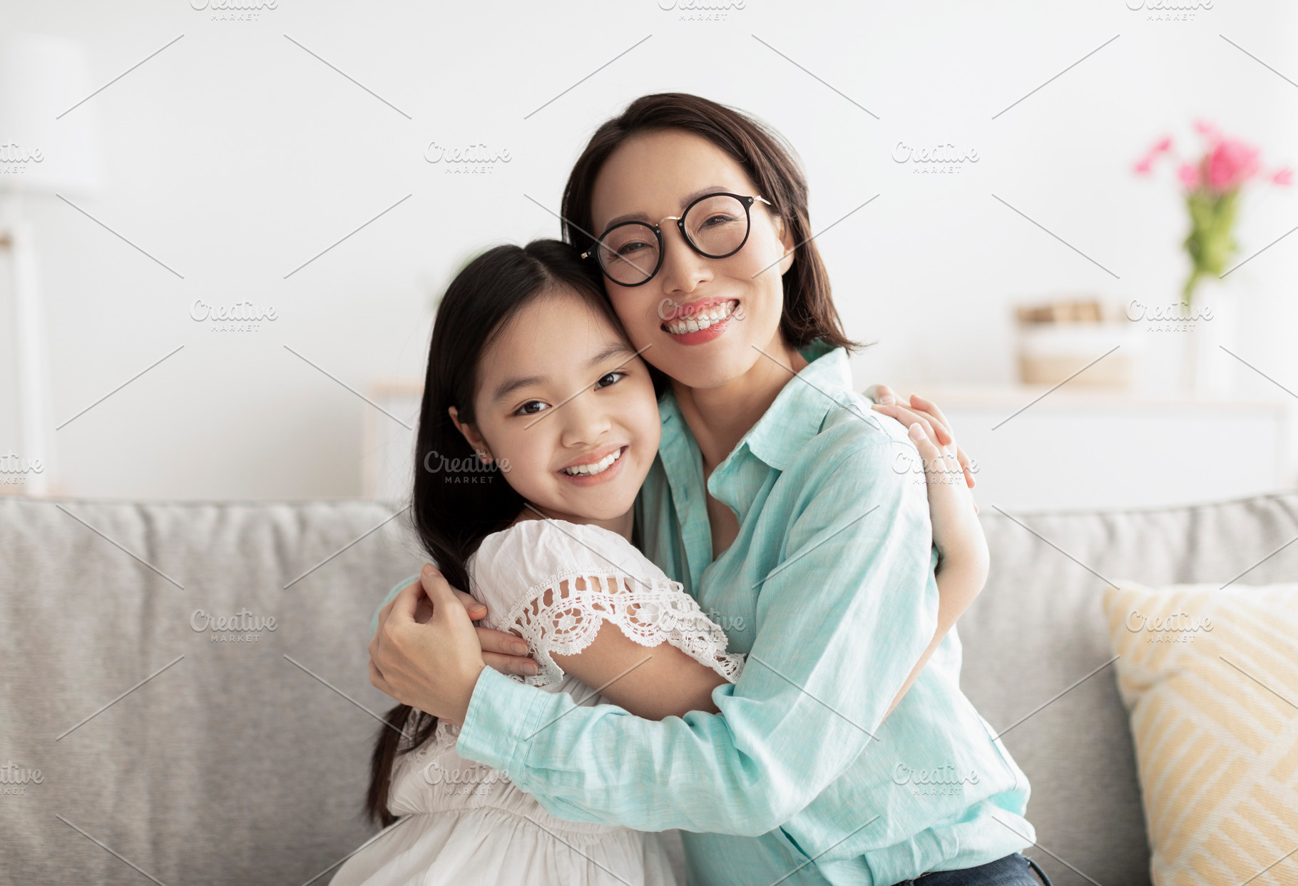 Happy little Asian girl and her loving grandmother hugging and looking at camer, a Photo by Prostock-Studio