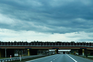Stormy sky over a highway with an overpass and approaching vehicles during dram, a Photo by AS photostudio