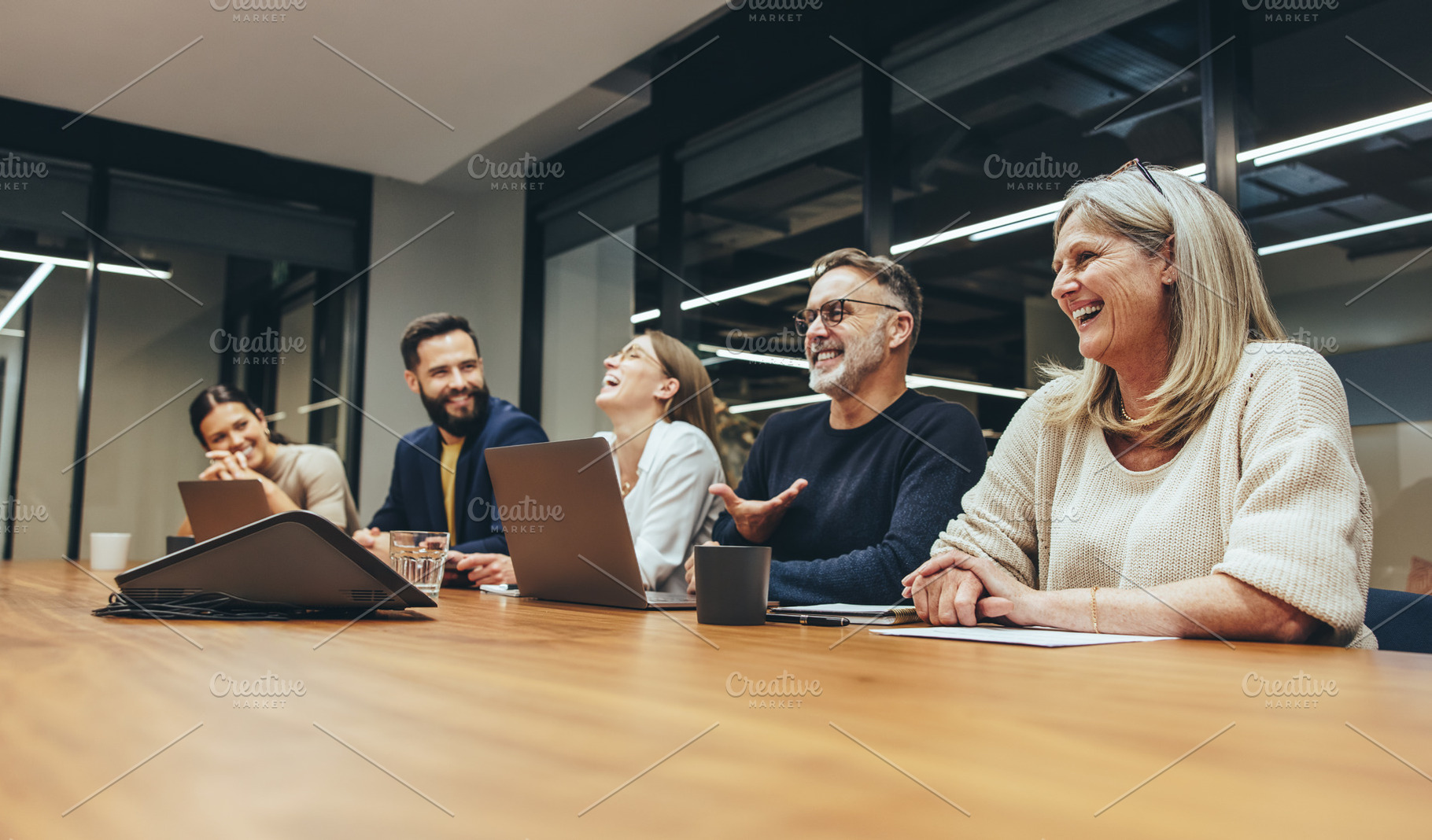 Cheerful businesspeople laughing during a meeting, a Person Photo by Jacob Lund