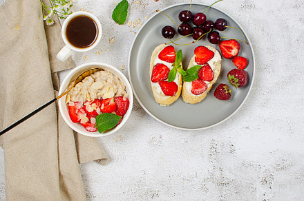 A bowl of oatmeal with strawberries and almond flakes on a table, a Food & Drink Photo by vimart