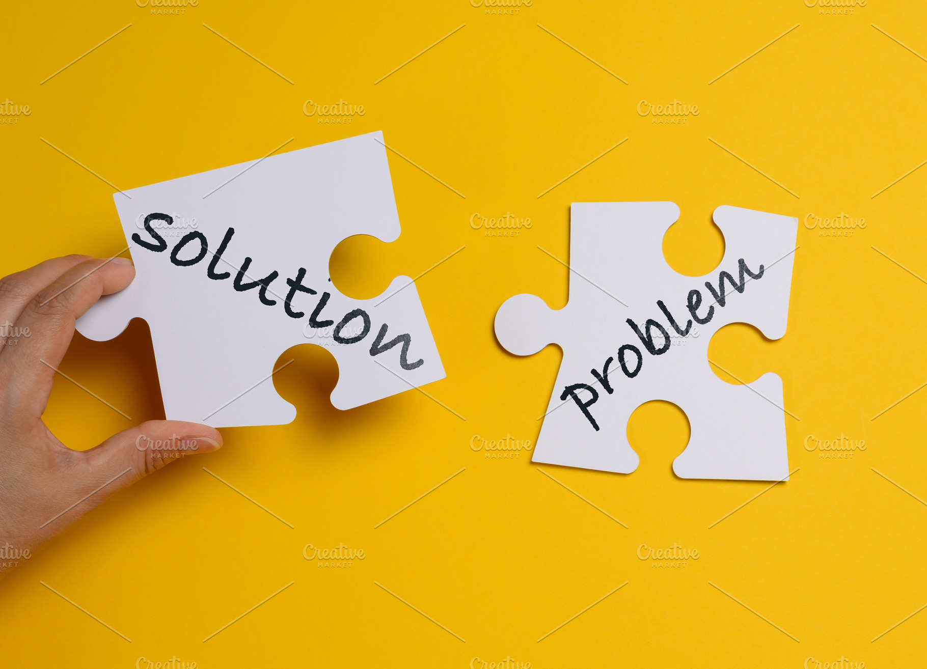 A person's hand connects two white puzzle pieces labeled solutio, a Background Photo by ndanko