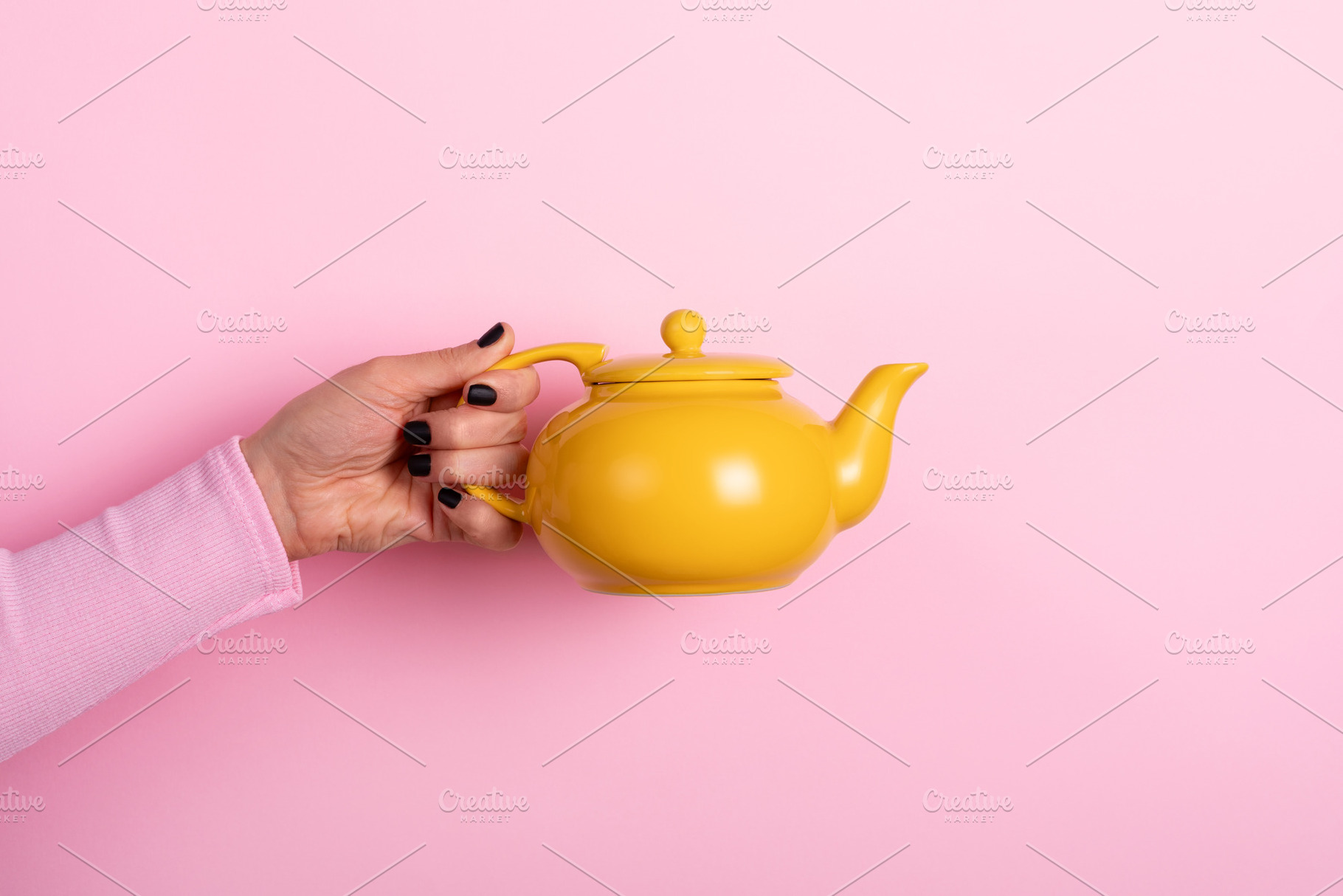 Hand holding a bright yellow teapot against a pastel pink backgr, a Food & Drink Photo by Ales Munt