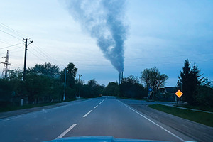 Empty rural road with TPP smoke rising into sky from distant chimney, a Photo by AS photostudio