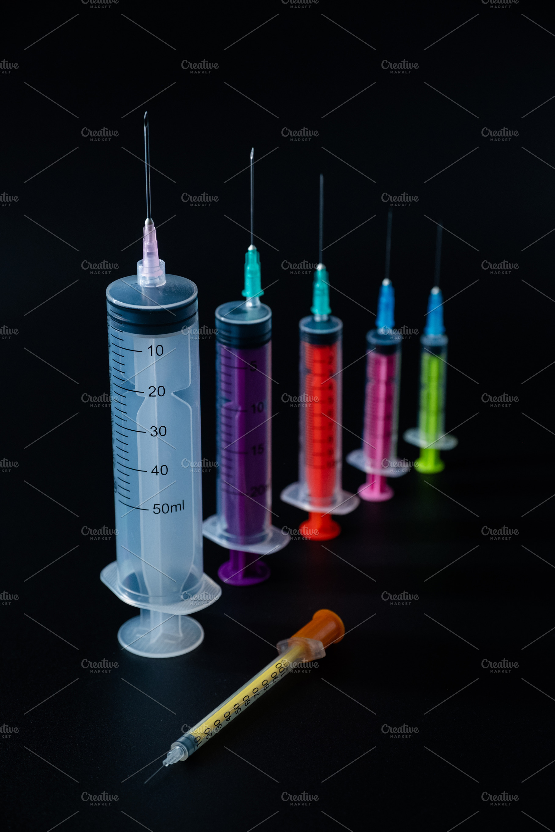 A vibrant lineup of various-sized syringes on a dark background, representing p, a Health & Medical Photo by Rohan Photography