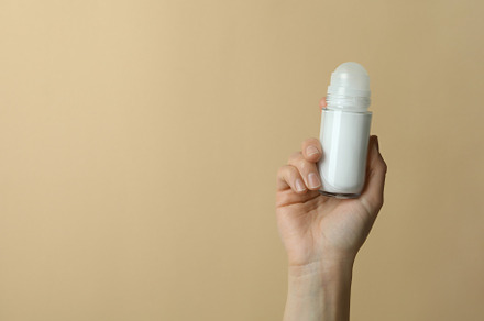 Female hand holds blank deodorant on beige background, a Health & Medical Photo by AtlasStudio