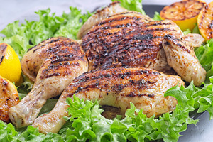 Spatchcocked grilled chicken with lemon garlic marinade on lettuce with lemon,, a Food & Drink Photo by iuliia_n