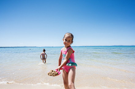 Happy children playing on a sunny beach with clear blue water and bright sky, a Person Photo by AS photostudio