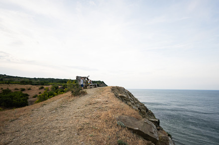 Bench with people on top of the hill with sea in the background., a Person Photo by AS photostudio