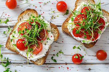 Sandwich with cream cheese, microgreens and tomatoes on wooden table, a Food & Drink Photo by AlyaAnd