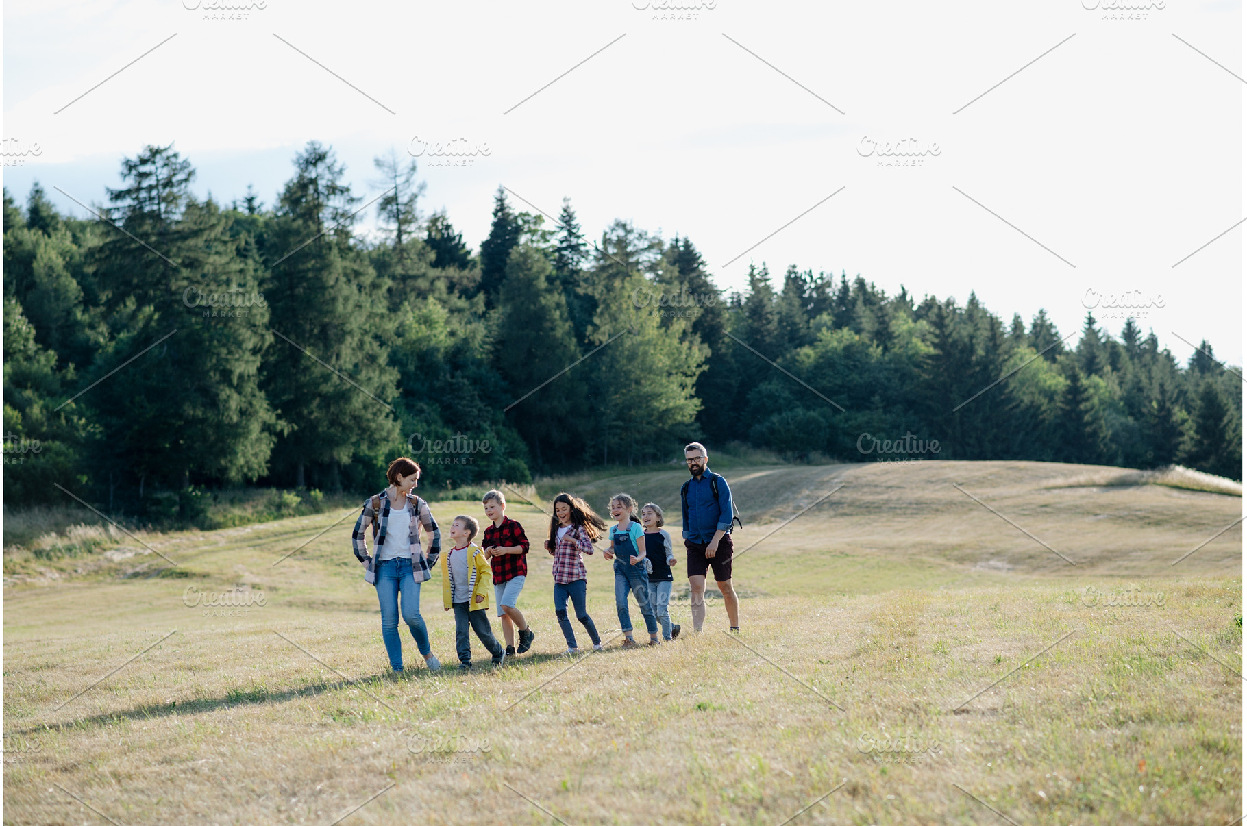 Young students walking across meadow, a Person Photo by HalfPoint