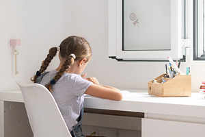 Young girl studying and writing homework at desk at home, a Person Photo by etorres69