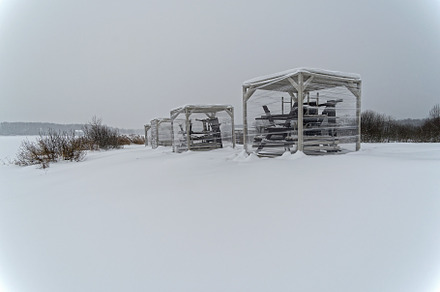 Closed-down for winter beach arbors on the shore of the lake.