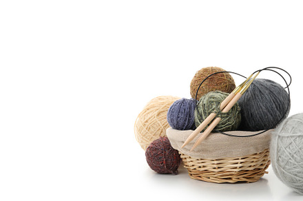 Balls of yarn with knitting needles in basket isolated on white