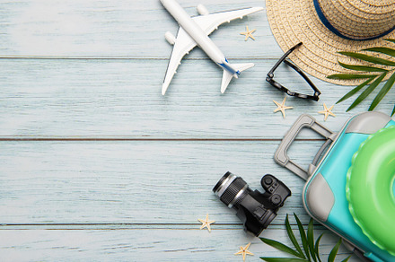 Travel accessories lying on wooden background for summer vacatio