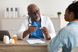 Experienced black doctor explaining treatment plan to patient, a Photo by Prostock-Studio