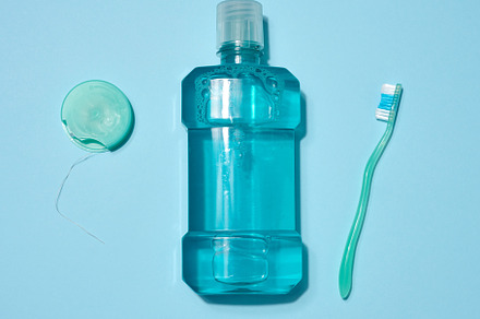 Bottle of blue mouthwash, dental floss in a blue case and green