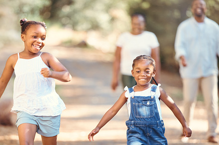 Black family, love and fun children run with smile, play and outdoor adventure with mother and father outdoor. Happy black woman and man with family and kids running, travel and on vacation in nature, a Photo by Peopleimages.com