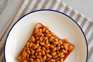 Homemade English Beans on Toast, top view. Overhead, from above,, a Food & Drink Photo by LiudmylaChuhunova