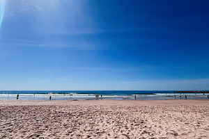 Sunny Lisbon Portugal beach scene with blue sky, sunlit shore, and people enjoy, a Photo by AS photostudio