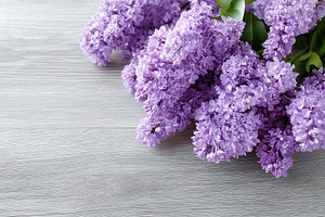 Vibrant lilac flowers arranged on a light wooden surface in a natural setting, a Nature Photo by AlyaAnd