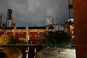 Night cityscape in Manchester with brick buildings canal and modern high rise u, a Photo by AS photostudio