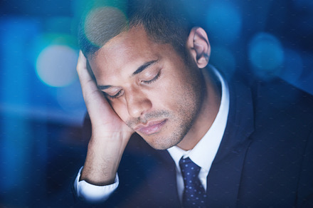 Tired, overworked and exhausted businessman sleeping while working overtime in the office at night. Fatigue, burnout and lazy corporate manager sitting at desk and taking nap in the company building., a Photo by Peopleimages.com