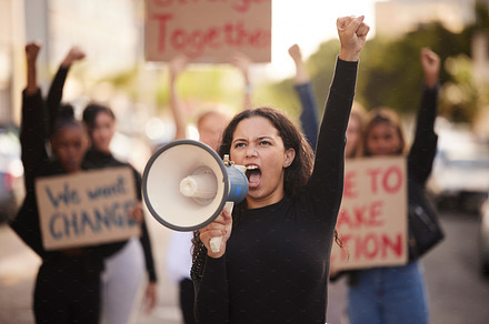 Woman, megaphone and fist in community protest for change, gender based violence or equality in the city. Angry women activist standing together in march strike for human rights or government action, a Photo by Peopleimages.com