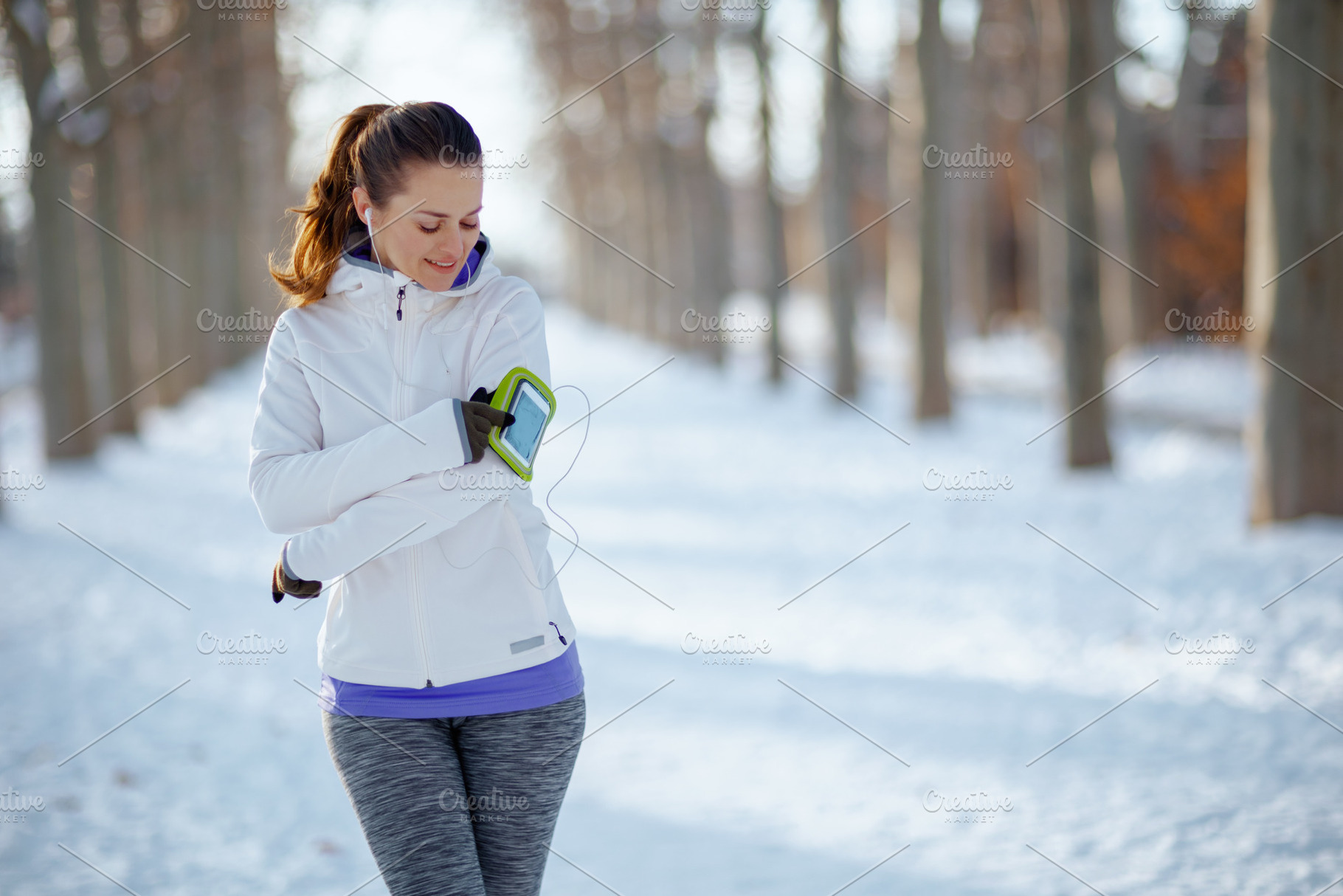 smiling fitness woman in white jacket with headphones, a Person Photo by Alliance Images