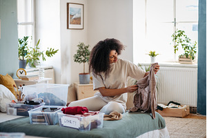 Young woman sorting wardrobe indoors