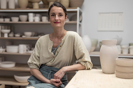 Portrait Of Smiling Mid Adult Potter Sitting In Workshop