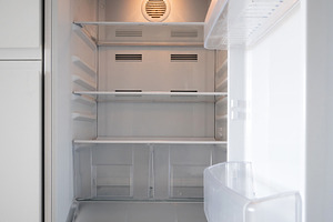 Empty open refrigerator with clean shelves in modern kitchen