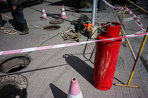 Workers performing maintenance on manholes with safety barricades and equipment, a Photo by AS photostudio