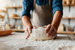 Baker's hands kneading dough in a rustic kitchen for fresh bread preparation, a Food & Drink Photo by AlyaAnd