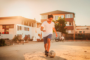 Teenager playing soccer in neighborhood street, a Person Photo by DanFLCreativo