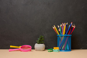 Multicolored pencils in a blue glass, a pink magnifying glass, e, a School & Education Photo by ndanko