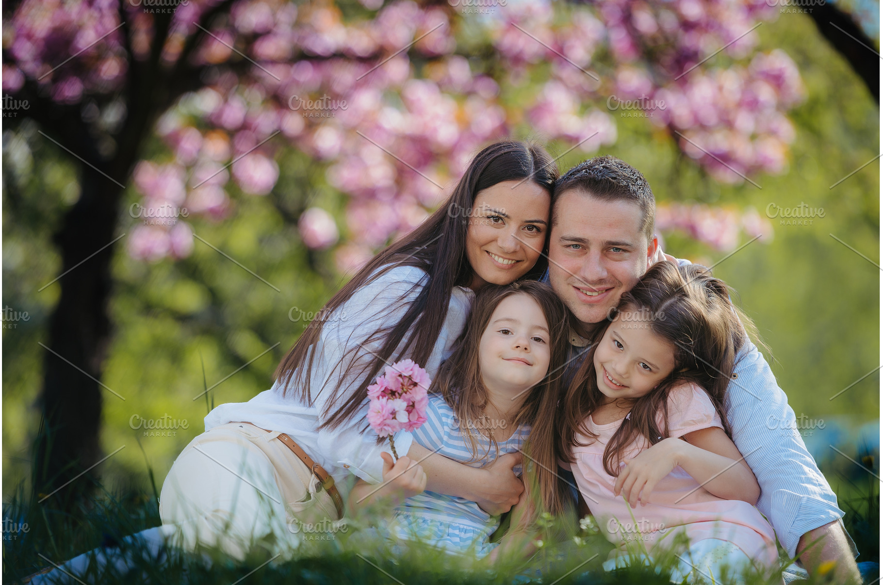 Family sittig on grass in blooming, a Person Photo by HalfPoint