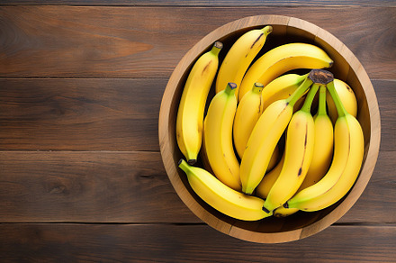Ripe bananas in bowl on brown wooden background, a Food & Drink Photo by AlyaAnd