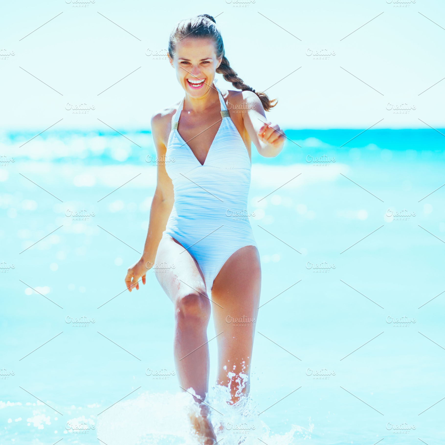 Happy young woman playing with water at seaside, a Person Photo by Alliance Images