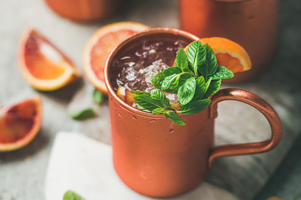 Blood orange Moscow mule alcohol cocktails in mugs on board, a Food & Drink Photo by Foxys