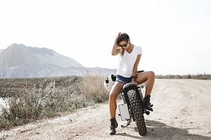 Woman and motorcycle on road stock photo containing background and retro, a Transportation Photo by Aliaksei Kaponia